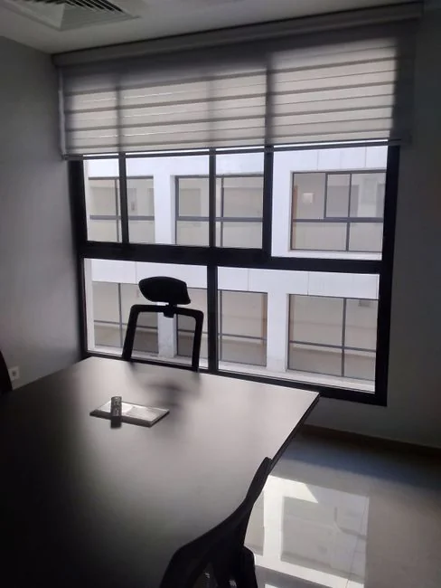 A roomy, modern office interior with glass dividers, elegant furniture, and colorful wall art.